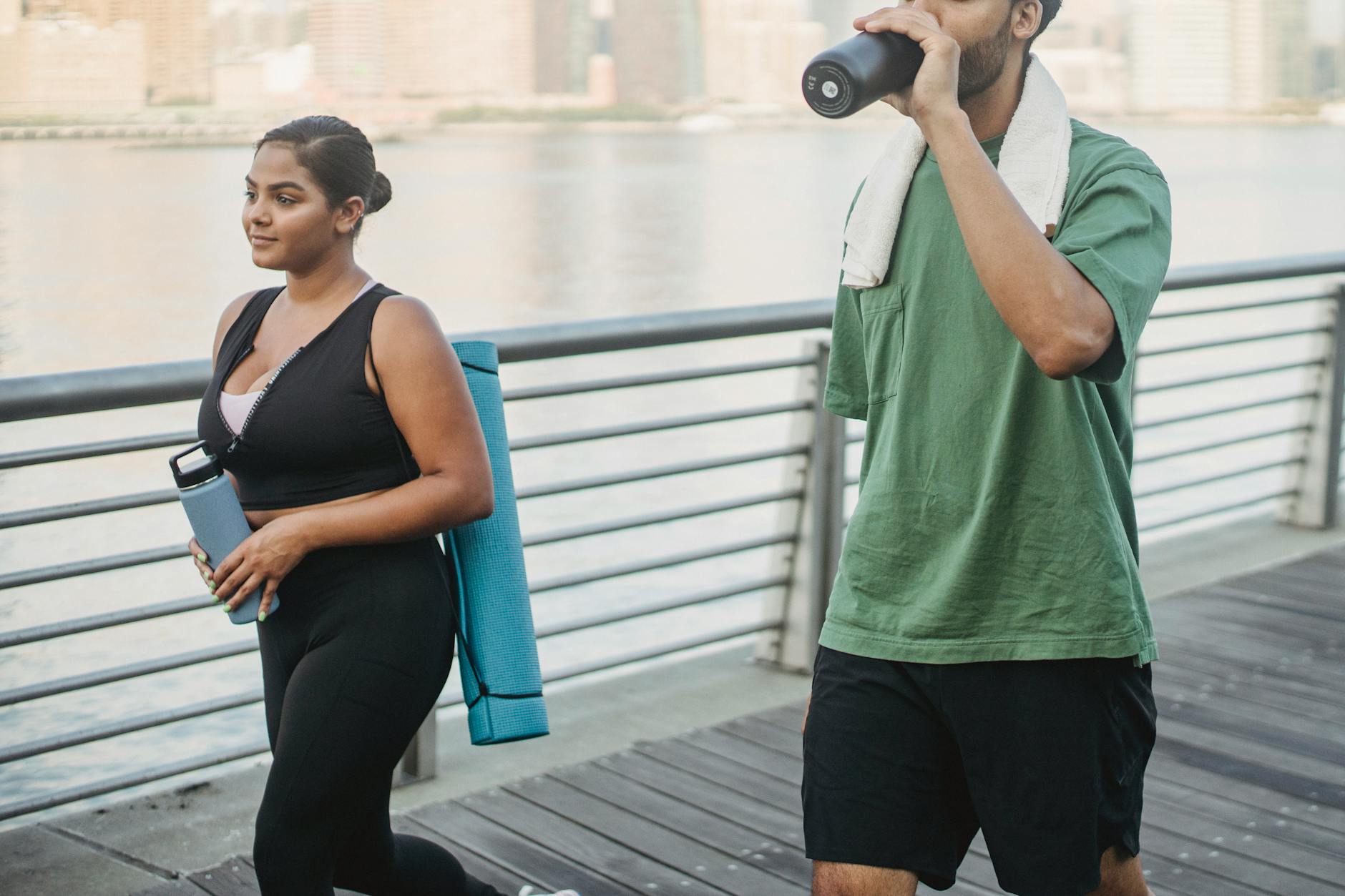 A couple engages in fitness walking by the riverside, embodying a healthy lifestyle. - outdoor workout hydration