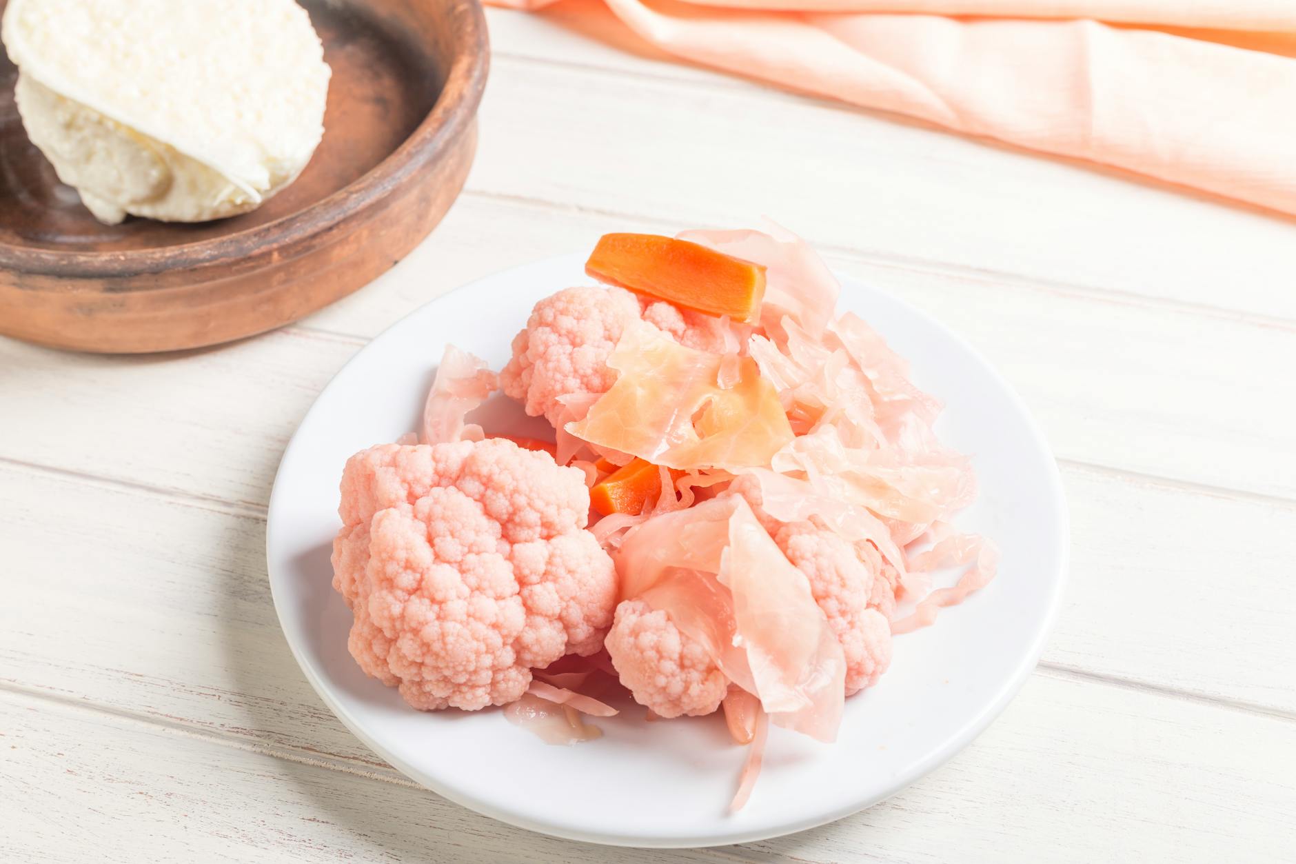 Pink pickled cauliflower and carrots on a white plate, perfect for culinary presentations. - probiotic recipes gut health