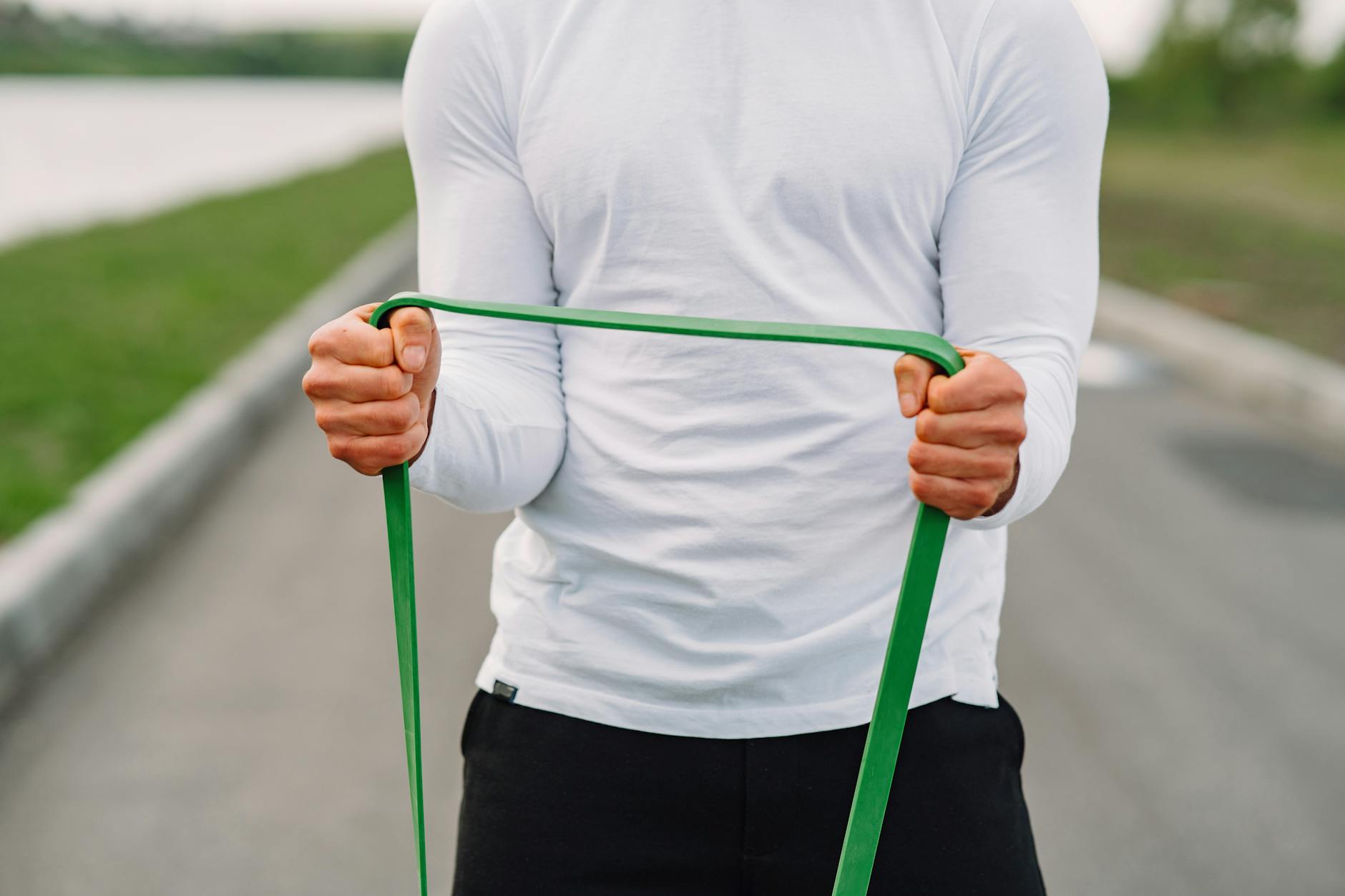 Man in sportswear using resistance band for outdoor fitness routine. - resistance band abs