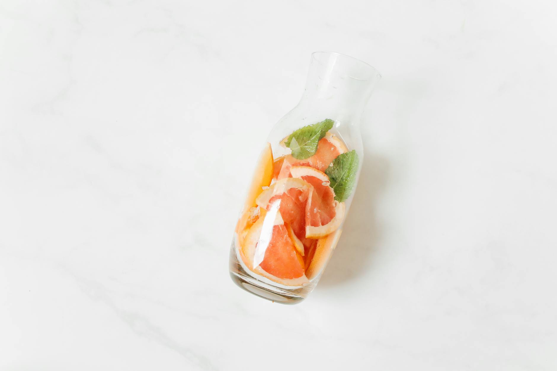 Top view of a citrus and mint infused water carafe on a light surface, perfect for a refreshing and healthy drink. - spring detox cleanse