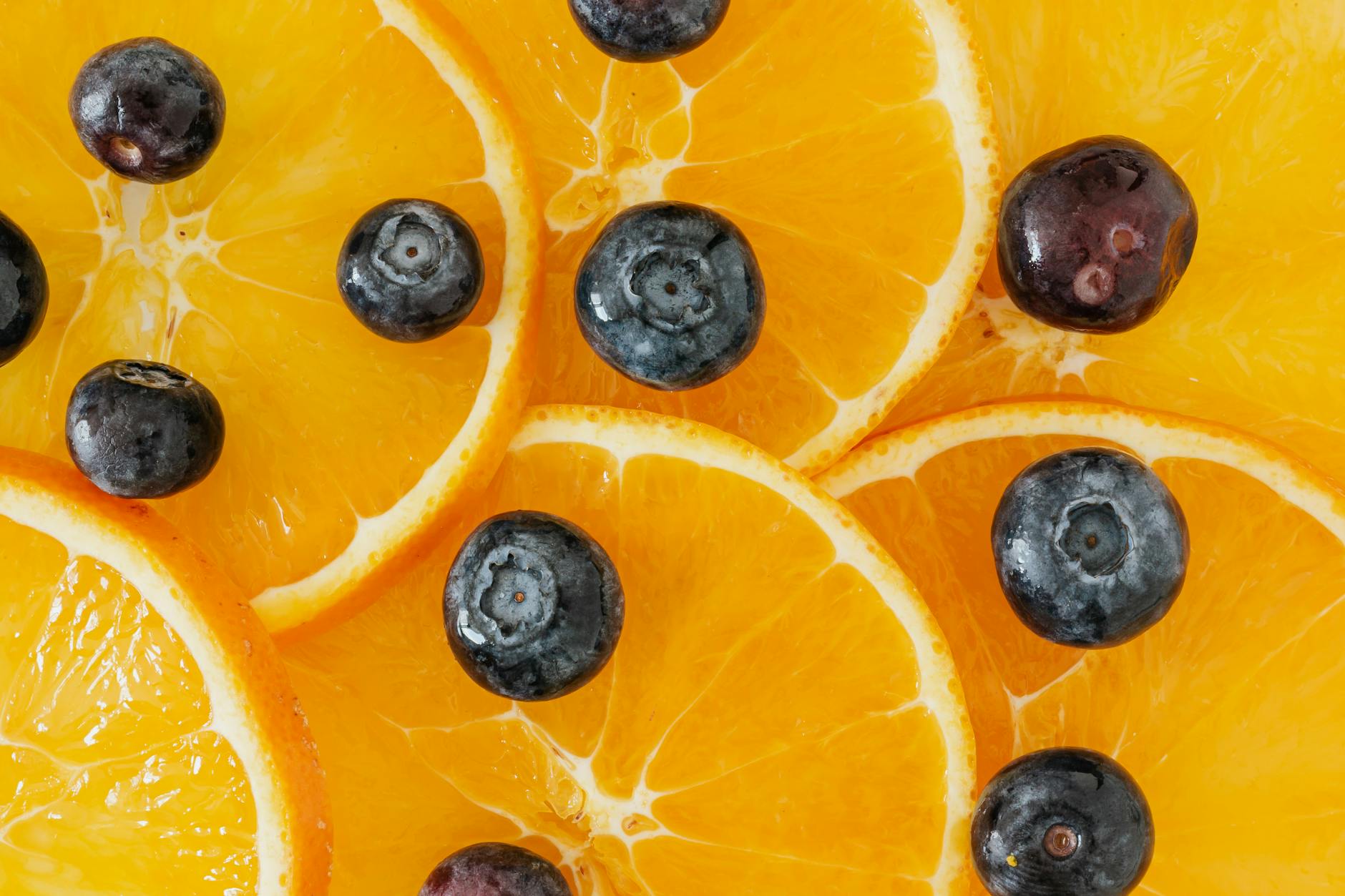 Top view closeup of slices of fresh ripe juicy orange and big blueberry - spring fruits energy