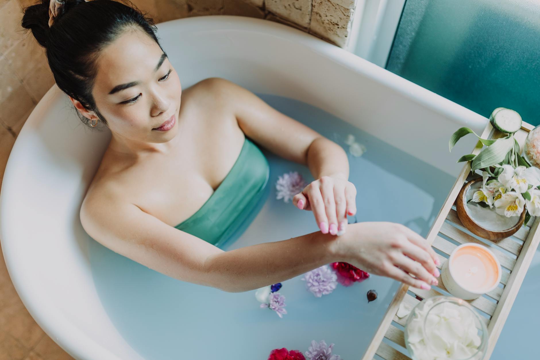 A woman enjoys a calming bath with flowers and candles, embodying self-care and relaxation. - spring self care