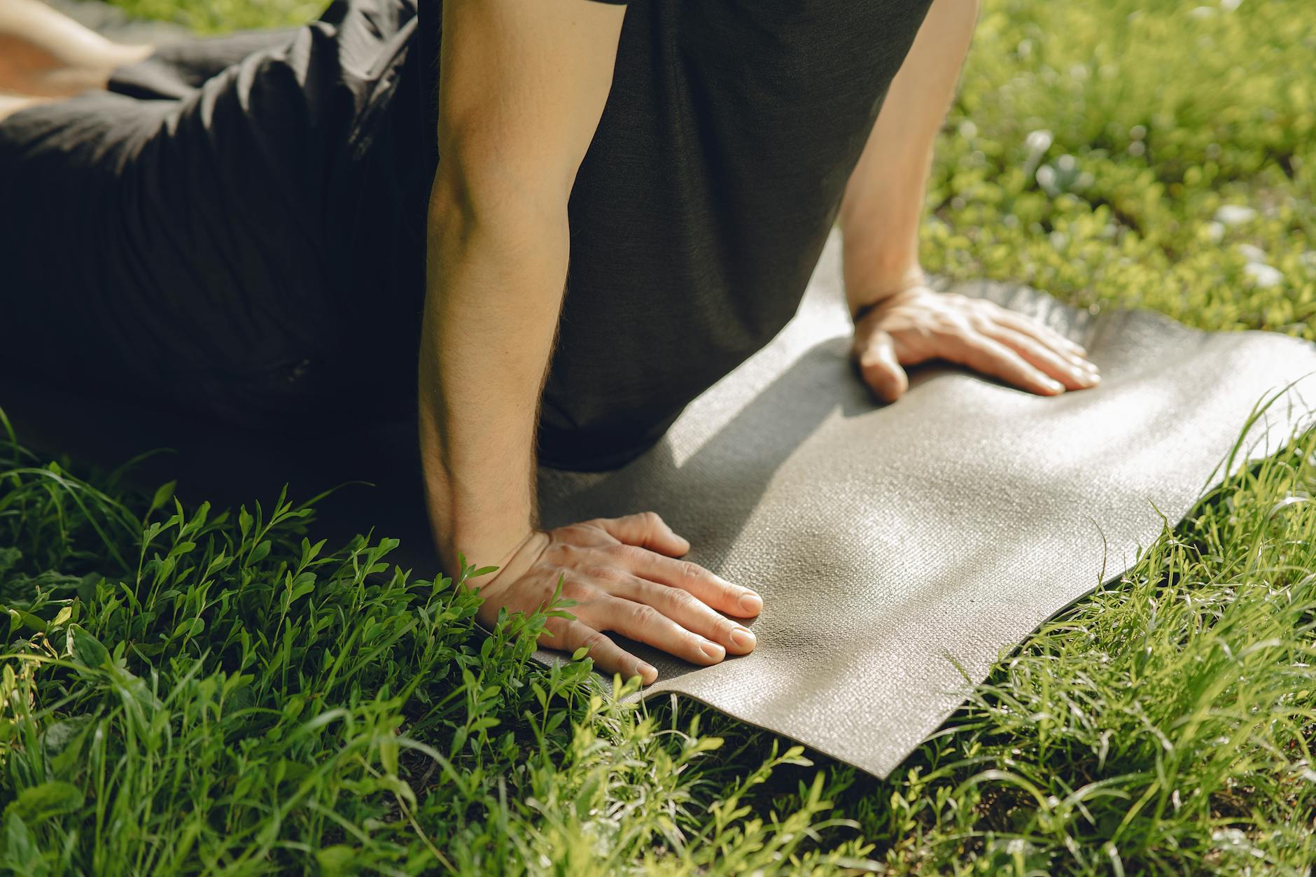 Man practicing yoga outside on a mat in a sunny park. - spring yoga renewal