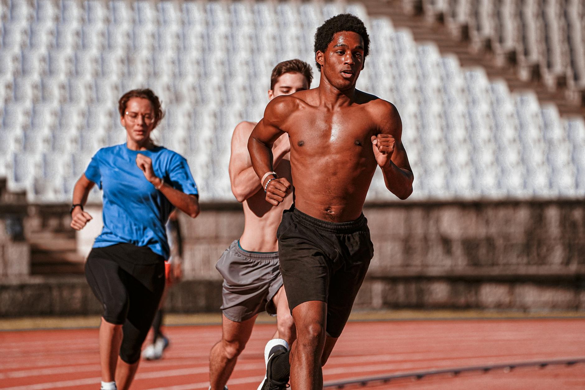 Group of athletes training on an outdoor running track, showcasing fitness and determination. - strength training runners
